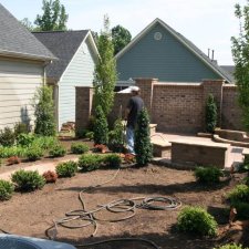Landscaping progress in backyard with contractor working and new plant beds