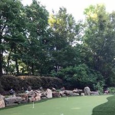 Backyard putting green surrounded by natural boulders and mature trees