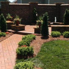 Brick garden walkway leading to raised planters and seating area
