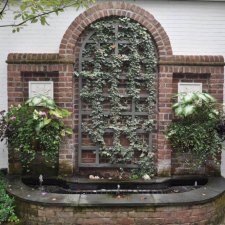 Brick wall fountain with ivy trellis and decorative planters