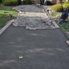 Crew installing paver driveway with edging and compacted base