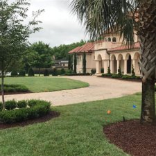 Large estate front yard with manicured lawn, foundation shrubs, and formal Mediterranean-style architecture
