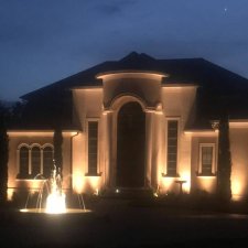 Front entry fountain and home facade highlighted with warm uplighting