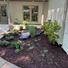 Freshly landscaped front yard with mulch, shrubs, and decorative slate stone feature