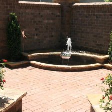Brick courtyard with tiered hardscape fountain and surrounding planters