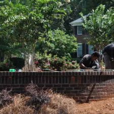 Crew constructing a curved brick retaining wall in a residential landscape