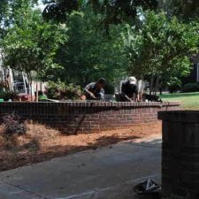 Crew constructing a brick retaining wall in a residential landscape