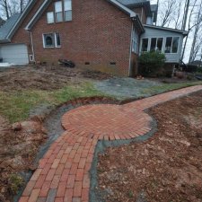 Curved brick walkway installation leading around residential landscape