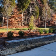 Curved stone retaining wall with landscaped planting bed