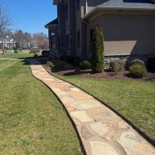 Flagstone pathway leading around side of home with manicured lawn