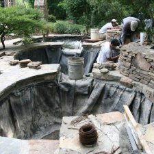 Stone pond construction with workers installing rock walls and lining