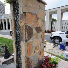 Stone column planter with stacked rock detail and fresh floral installation