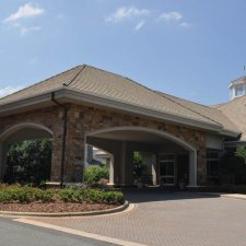 Stone-clad portico entrance with paved drive and landscaped surroundings