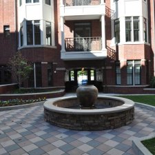 Commercial courtyard with circular stone fountain and patterned paver plaza