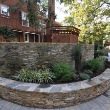 Curved retaining wall with landscaping and large elevated patio