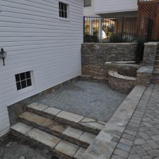 Finished retaining wall and paver patio with stone steps and curved wall