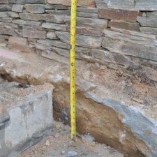 Close-up of retaining wall construction showing foundation depth measurement