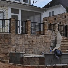 Multi-level stone retaining wall with black metal railing installation