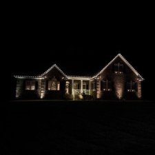 Home exterior with warm white holiday roofline lights at night