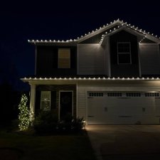 Two-story home with bright holiday roofline lighting at night