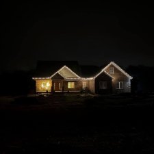House at night with clean white holiday string lights along the roofline