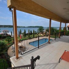 Lakefront home view overlooking landscaped yard, pool, and lake
