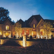 Evening uplighting on a luxury stone home with warm tones