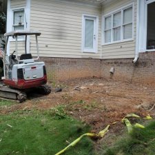 Excavation area beside home with mini-excavator clearing ground