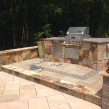 Stone outdoor kitchen setup with stainless steel grill and counter space
