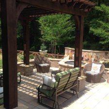 Lounge seating beneath a wooden pergola in a landscaped backyard