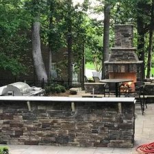 Backyard patio featuring a stone fireplace and dining area
