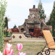 Outdoor living space featuring a large stone fireplace and cushioned seating