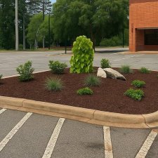 Parking lot island with mulch shrubs ornamental grass and accent boulders