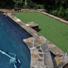 Poolside stonework with artificial turf and raised seating wall