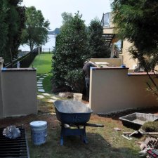 Retaining wall installation near lakeside property with workers on site