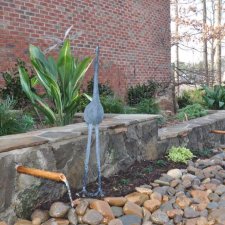 Decorative outdoor stone fountain with spouts and surrounding garden beds