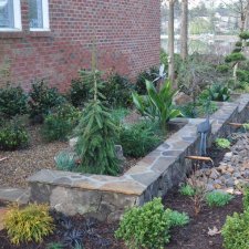 Tiered stone garden bed with copper water spouts and lush planting