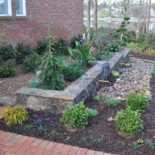 Stone raised garden beds with flowing copper spouts and landscape plants
