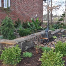 Decorative stone wall with water spouts and mulched planting area
