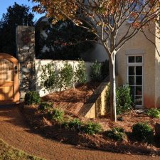 Stone gate entry with garden path, shrubs, and landscaped beds