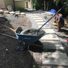 Landscape construction showing large stone pavers being installed along a curved pathway