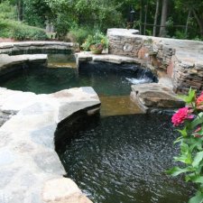 Elevated stone pond with flowing water and lush plants