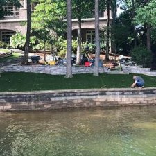 Workers installing artificial turf on lakeside retaining wall