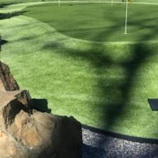 Artificial turf putting green with golf flags and stone boulders