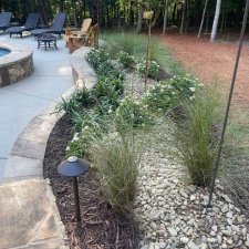 Workers installing new landscape beds with brick walkway and fresh plantings